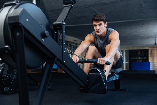 young man using rowing machine in the gym