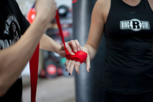 Wrapping a boxer's hands with a red handwrap, a key piece of boxing gear.