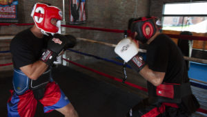 Two fighters wearing sparring headgear square off in the ring.