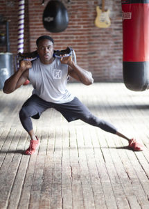 agility training for boxing - athlete doing side lunge with weighted sand bag on shoulders