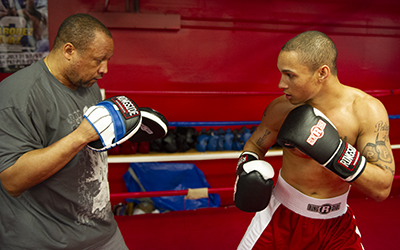 A coach provides feedback to a boxer during mitt-work.