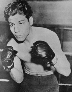 Manuel Ortiz posing in the ring with boxing gloves on.