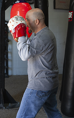 Coach has feet set and mitts up. He is prepared to catch the next punch and then react.