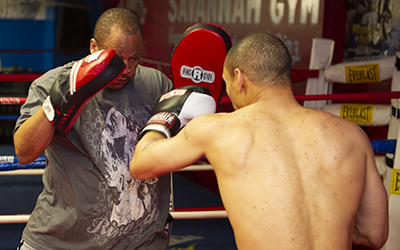 Coach prepares to receive a hook punch into his punch mitt.