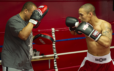 Coach with punch mitts holds mitts read to receive a jab.