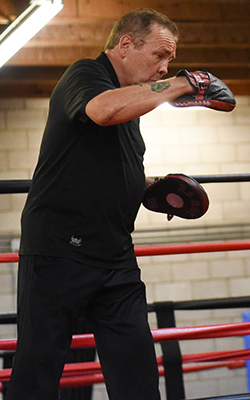 Boxing coach holds the punch mitt appropriately for an uppercut.