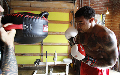 Boxer prepares to hit punch shield with an uppercut.