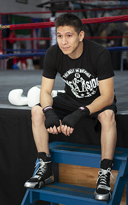 A boxer sits on the ring stairs thinking about his most recent training session.